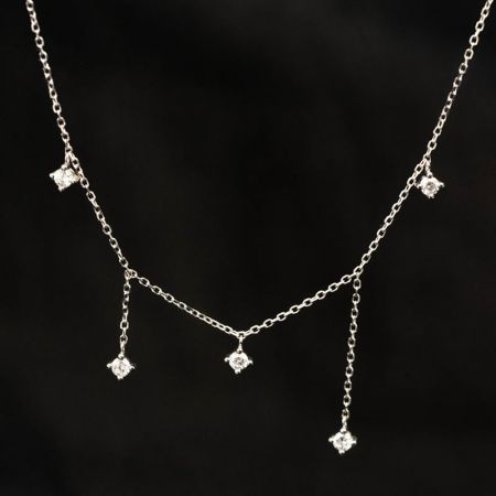 Scatto dettagliato della collana con pendente a nappina in argento su uno sfondo neutro.