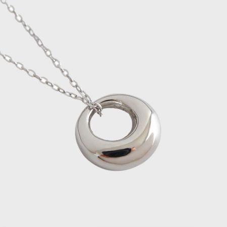 Gros plan détaillé du pendentif rond géométrique en argent sterling 925, mettant en avant sa finition brillante et son design minimaliste.