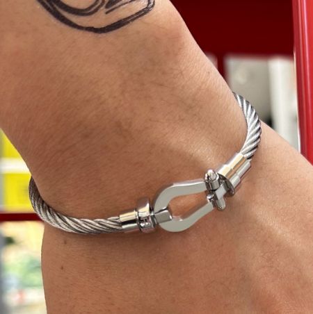 Wire Bangle Bracelet For Men - A man wearing a stylish silver stainless steel wire bangle bracelet with a distinctive twisted design and oval clasp.