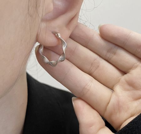 Een model die de 925 sterling zilveren gedraaide creolen draagt om de schaal en het uiterlijk te tonen.