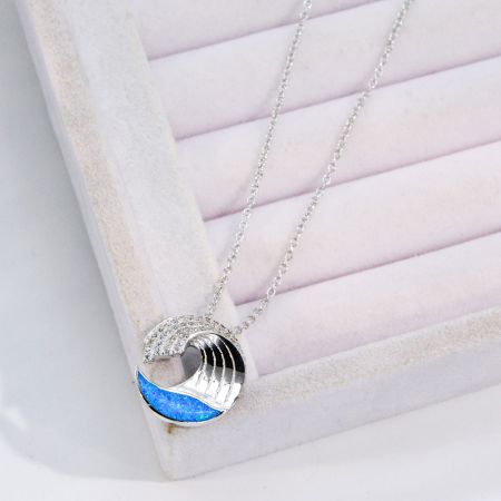 Full view of the silver wave necklace with its vibrant blue opal pendant.