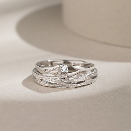 Detailed view of the silver ring with a unique wavy design and a central gemstone.