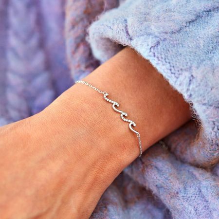 Pulsera Curva Elegante Glittering Waves en Plata de Ley 925 - Un primer plano de la elegante pulsera curva Glittering Waves en plata de ley 925, llevada en una muñeca, mostrando su diseño ondulado y piedras de circonio brillantes.