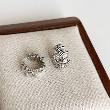 Due paia di orecchini in argento con pieghe irregolari esposti per mostrare angolazioni diverse.
