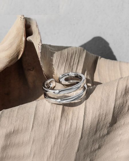 Bague à double lignes en argent sterling 925 - Une bague à double lignes en argent sterling 925 magnifiquement conçue avec un design ondulé unique, reposant sur une feuille verte.