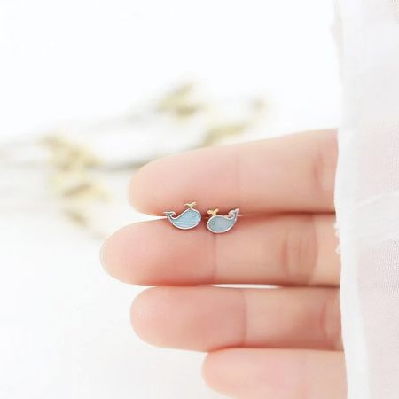 Whale stud earrings held in hand to provide a sense of scale and craftsmanship.