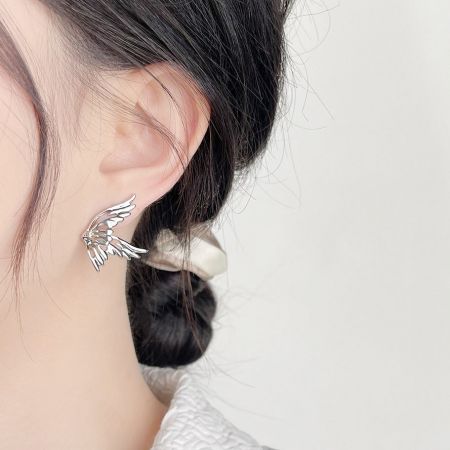 Primo piano di una donna che indossa un orecchino a bottone a forma di farfalla placcato in argento, che mostra il suo design delicato.