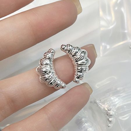 Une main tenant les boucles d'oreilles en argent en forme de croissant pour montrer l'échelle et les détails.