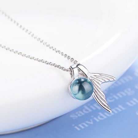 Collana in argento con un pendente unico a forma di ali e un orbe blu centrale.