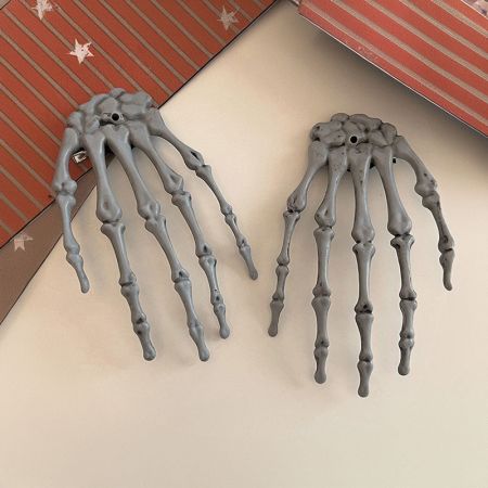 Dos clips de pelo en forma de mano esqueleto exhibidos contra un fondo blanco para mostrar los detalles del producto.