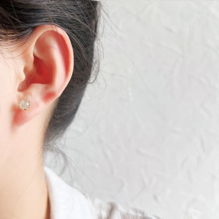 白のシマー石スタッドピアスの微妙なエレガンスを披露するモデル。