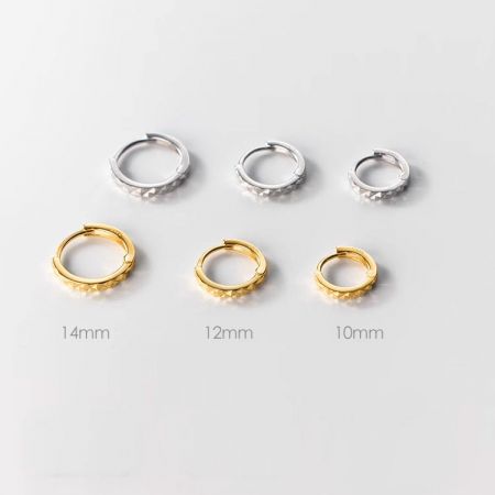 Aros huggie minimalistas de plata esterlina con corte de diamante. - Una colección de pendientes huggie minimalistas de plata esterlina 925 disponibles en acabados de plata y oro, con tamaños de 10mm, 12mm y 14mm exhibidos.