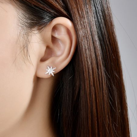 Modèle portant les boucles d'oreilles Huggie Hoop Starburst pour mettre en valeur leur taille et leur style.
