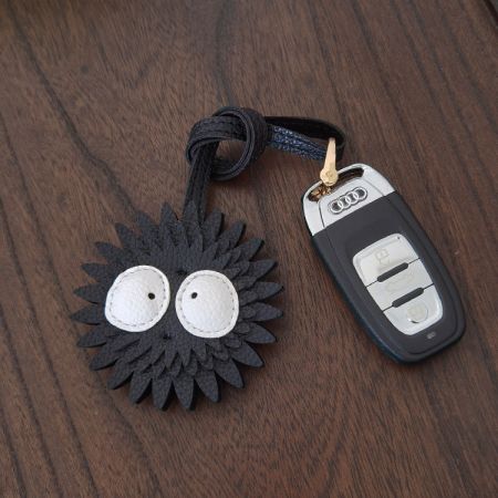 Soot Sprite leather keychain attached to an Audi car key fob, demonstrating its use as a car key holder.