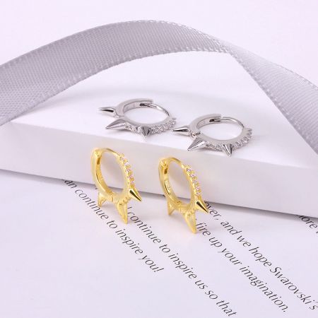 Orecchini a cerchio huggie punk in argento sterling 925 con rivetti (5 paia) - Un paio di orecchini a cerchio huggie punk in oro e un paio in argento 925 esposti affiancati su uno sfondo bianco.