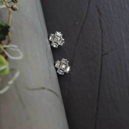 Un paio di orecchini a cubo di ghiaccio in argento con gemme chiare disposte in un motivo quadrato.