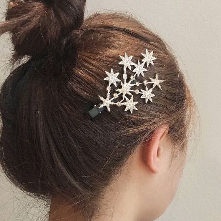 Primo piano della clip per capelli a forma di stella elegantemente posizionata in un raccolto di capelli.
