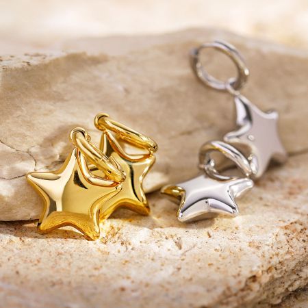 Vista ravvicinata dei ciondoli a forma di stella in oro e argento, evidenziando la loro finitura lucida.