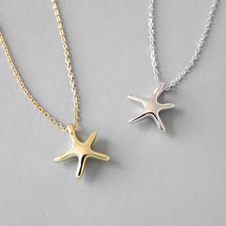 Collar de estrella de mar geométrico simple de plata esterlina 925 - Un par de collares de estrella de mar de plata esterlina 925, uno con un acabado plateado pulido y el otro con un acabado dorado radiante, exhibidos uno al lado del otro.