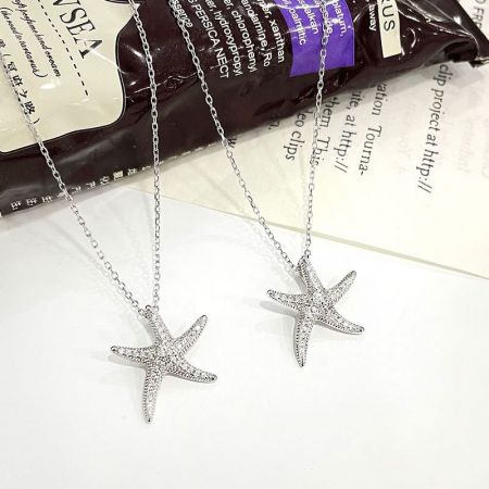 Collar de estrella de mar de plata esterlina 925 con piedras CZ pavé de playa. - Un par de collares de estrella de mar de plata esterlina 925 del conjunto, con piedras CZ pavé brillantes sobre un fondo blanco.