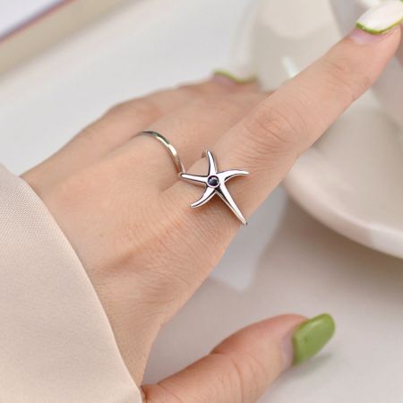 Set di 5 anelli aperti regolabili a forma di stella marina in argento sterling S925. - Una modella che indossa l'anello regolabile a forma di stella marina in argento sterling S925 con una pietra nera centrale, mostrando il suo elegante design a tema oceanico.