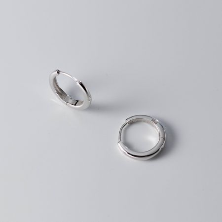 Primo piano degli orecchini a cerchio minimalisti in argento sterling 925, che mostrano la finitura di alta qualità e il design classico.