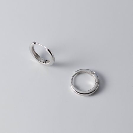 Scatto dettagliato degli orecchini a cerchio in argento sterling, evidenziando il marchio '925' che certifica la purezza del materiale.