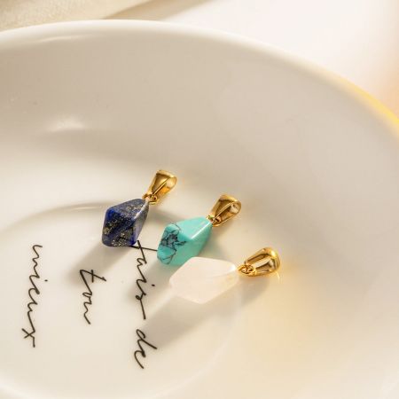 Vue rapprochée des pendentifs en pierre naturelle avec des fermoirs en or durables.