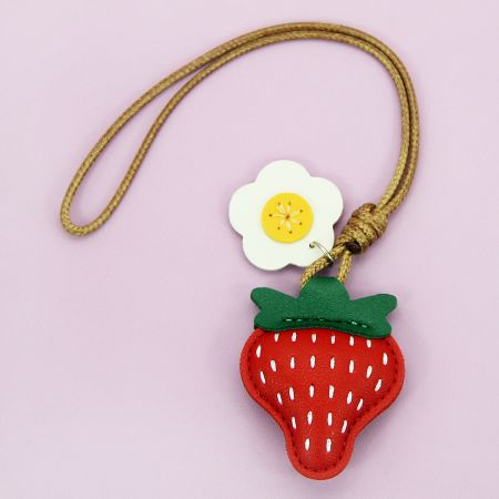 Une variation du porte-clés en forme de fraise avec un petit charme en forme de fleur blanche.