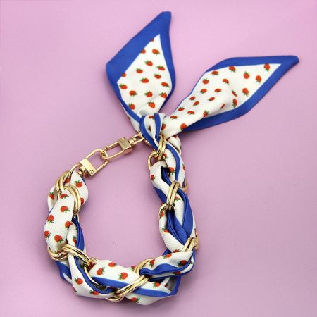 明るい青い背景に遊び心のあるイチゴパターンの編み携帯ストラップ。