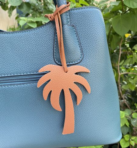 Un porte-clés en cuir de cocotier marron complétant un sac à main bleu teal.