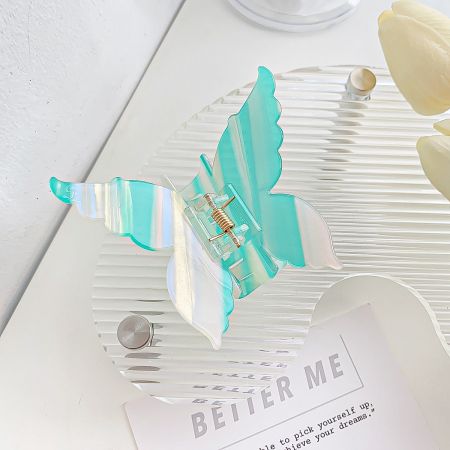 A detailed view of a teal and white striped butterfly hair clip.