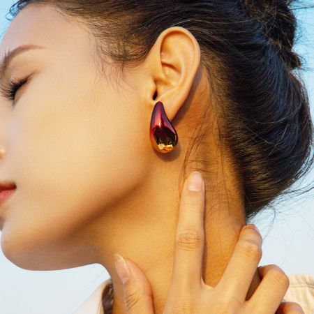 Primer plano de una mujer que lleva un elegante pendiente en forma de lágrima de acero inoxidable con degradado.