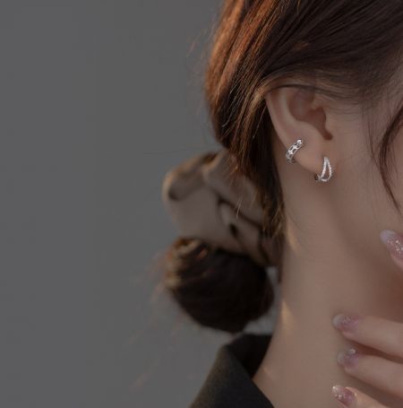 Primo piano di un modello che indossa un orecchino a cerchio in argento sterling a forma di goccia.
