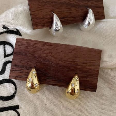 Orecchini a cerchio larghi chunky con stella in zirconia 925 in argento sterling (set da 5 paia) - Un paio di orecchini a cerchio chunky in argento sterling 925 e un paio di orecchini a cerchio in oro, entrambi con un design a stella prominente con accenti in zirconia, esposti fianco a fianco.