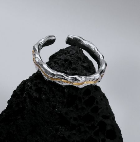 Bague en argent sterling 925 avec double plaquage - Un gros plan de la bague en argent sterling 925 avec double plaquage, mettant en valeur sa finition texturée unique avec des accents dorés élégants, reposant sur une surface naturelle sombre.
