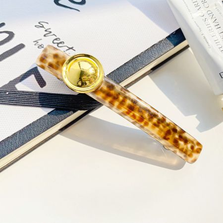 Detailed shot of a tortoiseshell pattern acetate hair clip with a polished gold detail.