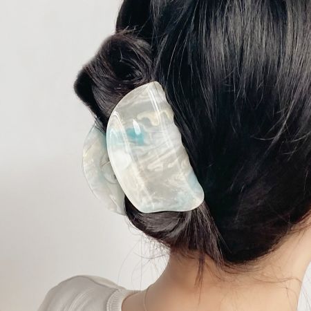 Una mujer con un peinado de moño que lleva un gran clip de pelo semicircular translúcido.