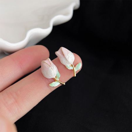 手がチューリップ型のピアスを持ち、その繊細なサイズと職人技を示しています。