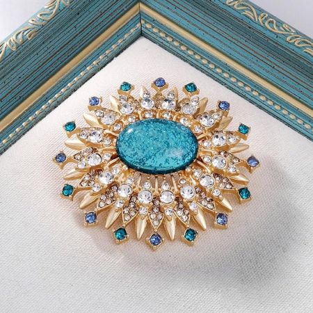 Volledig zicht op de goudkleurige zonnestraal broche met een levendige turquoise centrale steen, perfect voor een bohemian look.