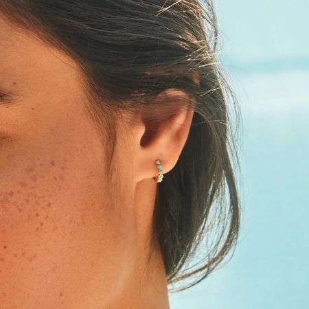 Profil latéral d'une femme portant une boucle d'oreille en turquoise en argent sterling 925.