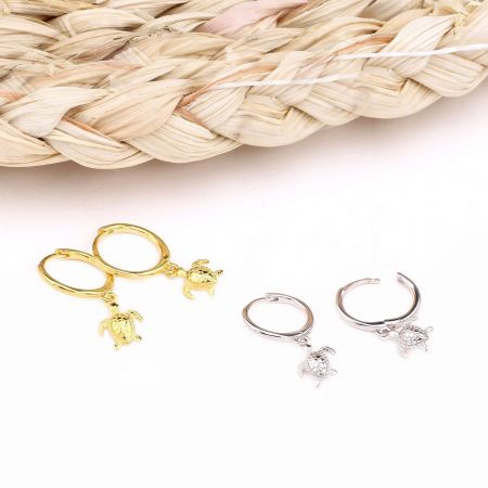Orecchini a cerchio huggie in argento sterling 925 a forma di tartaruga marina - Un paio di orecchini huggie a forma di tartaruga oceanica in argento sterling 925 mostrati in finiture dorate e argentate, evidenziando il design dettagliato del ciondolo a forma di tartaruga.