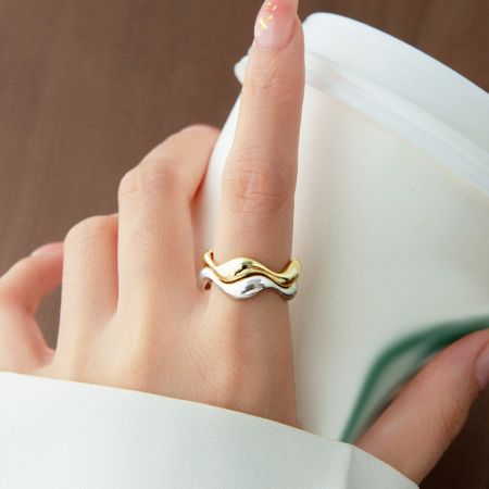 Close-up van een twee-tonige golvende ring van 925 sterling zilver, met zowel gouden als zilveren afwerkingen.