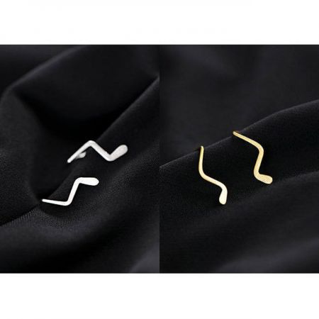 Due paia di orecchini a linea ondulata in argento e oro, evidenziando il design minimalista.
