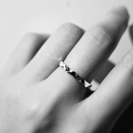 The minimalist wavy band ring worn on a finger, highlighting its elegant and stackable design.