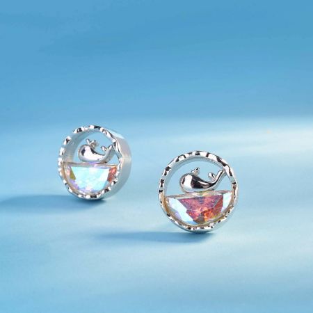 Un paio di orecchini a forma di balena in argento sterling mostrati da un'angolazione diversa per evidenziare la qualità iridescente delle gemme di opale.