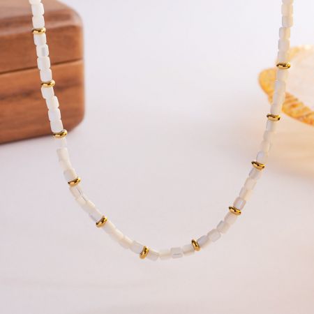 Detailed view of the white shell beads and gold accents on the choker necklace.