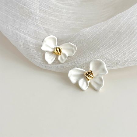 A detailed close-up of the white enamel knot bow earrings, highlighting the intricate gold center and craftsmanship.