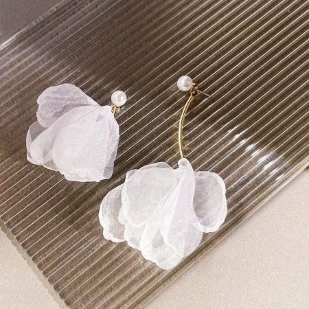 エレガントなゴールドの茎とパールの中心を持つ白い花のイヤリングのペアが、中立的な背景に展示されています。