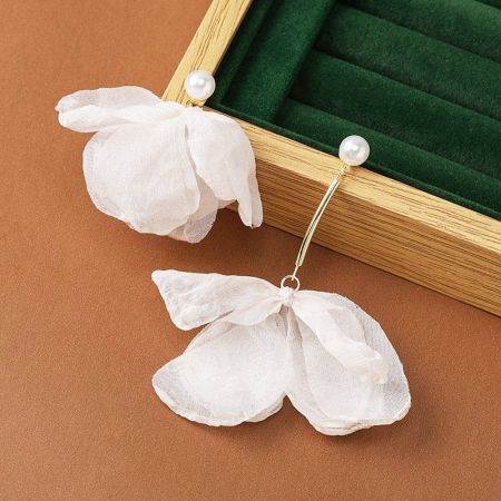 パールスタッド付きの白い花のイヤリングの複雑な布のような質感を示す製品写真。